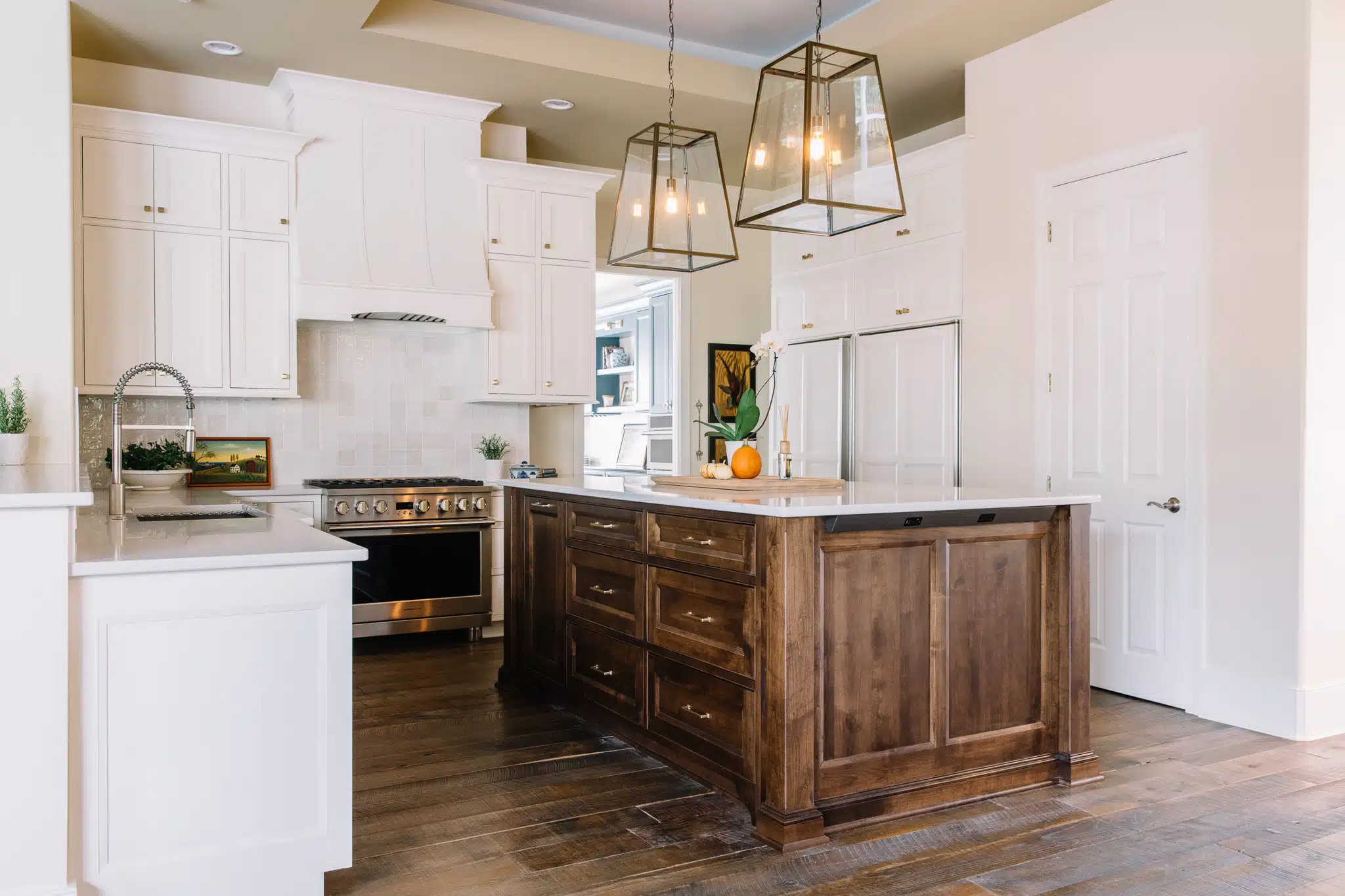 A white kitchen with a brown island and integrated appliances.