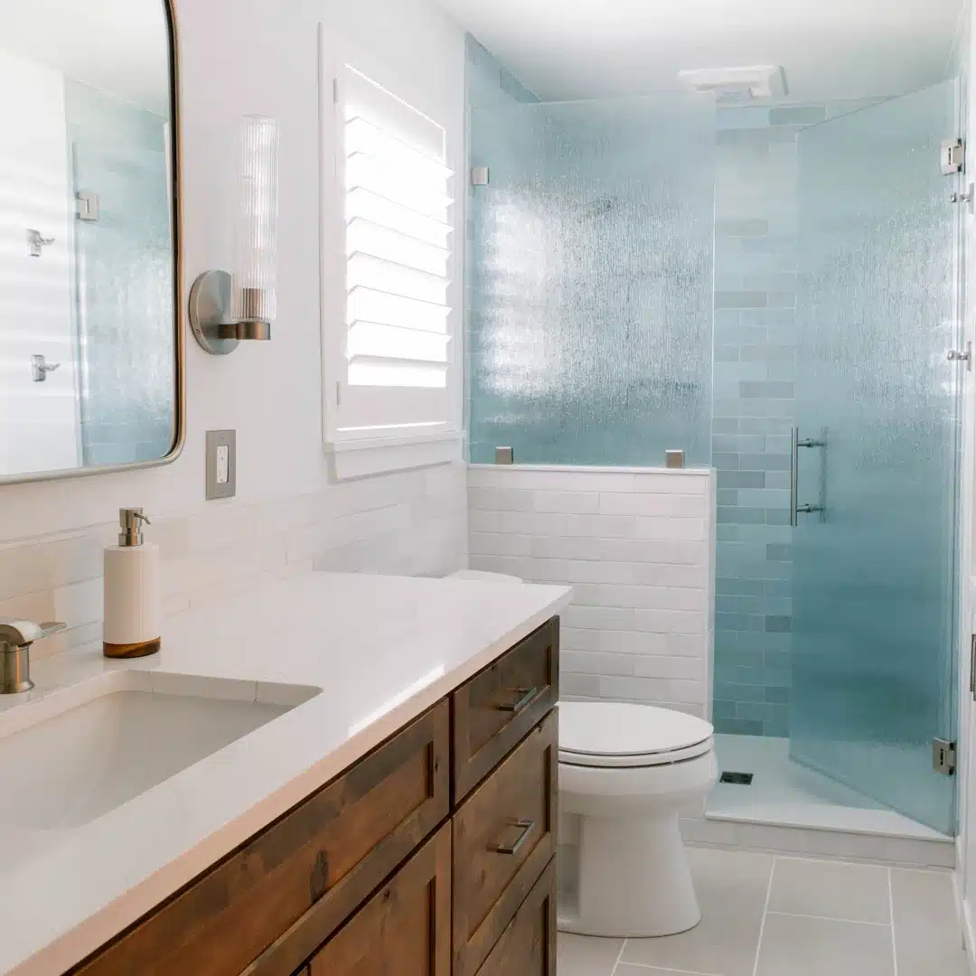 small bath remodel with wood vanity, white countertop, and blue glass tile shower in Potts Bathroom