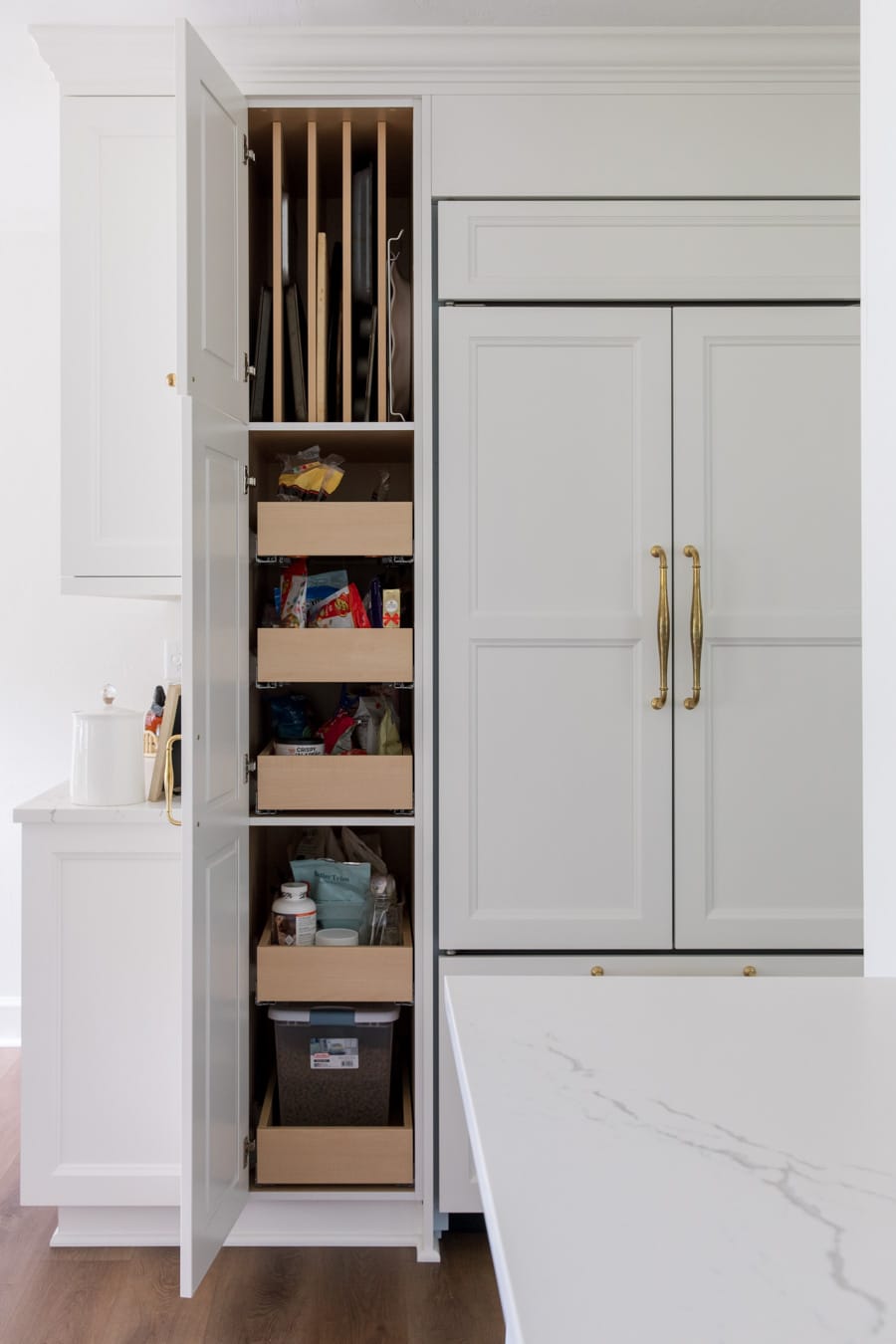 Tall pantry cabinet with rollouts next to paneled fridge